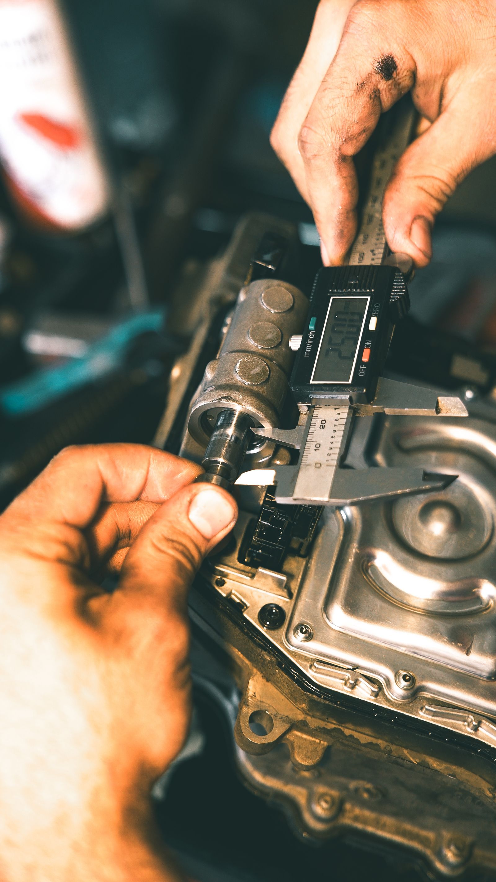 Hands checking a metal component with a digital caliper